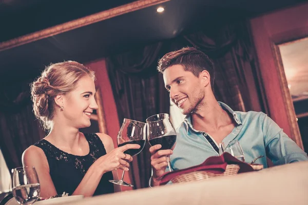 Beau jeune couple avec des verres de vin au restaurant — Photo