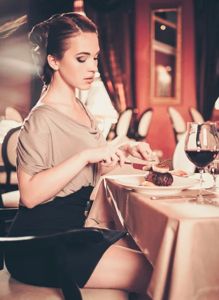 Beautiful young woman eating alone in a restaurant — Stockfoto