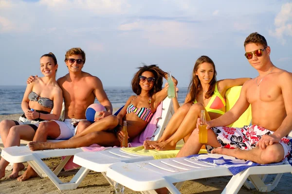 Grupo de amigos multiétnicos con bebidas relajantes en una playa —  Fotos de Stock