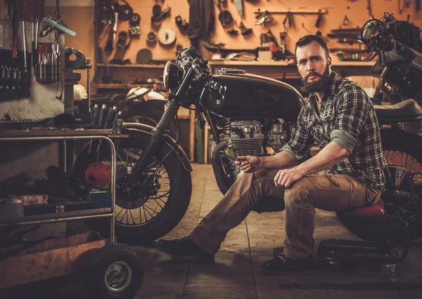 Mechanic building vintage style cafe-racer motorcycle  in custom garage — Stock Photo, Image