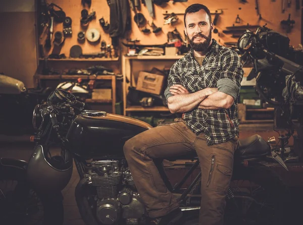 Rider and his vintage style cafe-racer motorcycle in customs garage — Stock Photo, Image