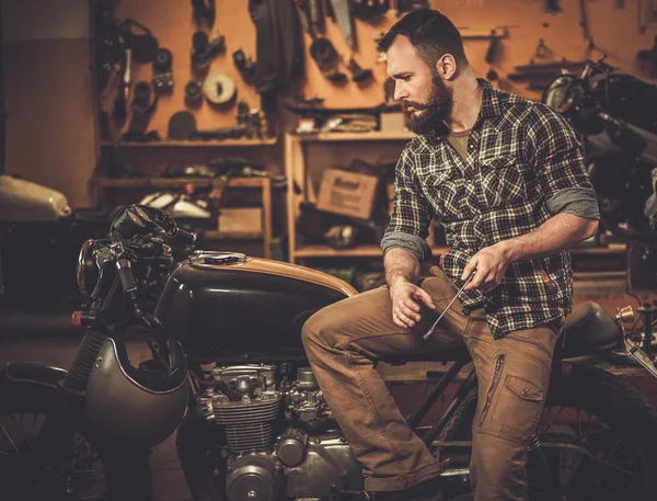 Binici ve vintage tarzı kafe-yarış motosikleti gümrük garajda — Stok fotoğraf