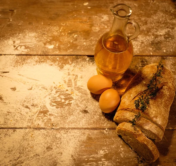 Homemade bread, oil and eggs on a table — Stock Photo, Image