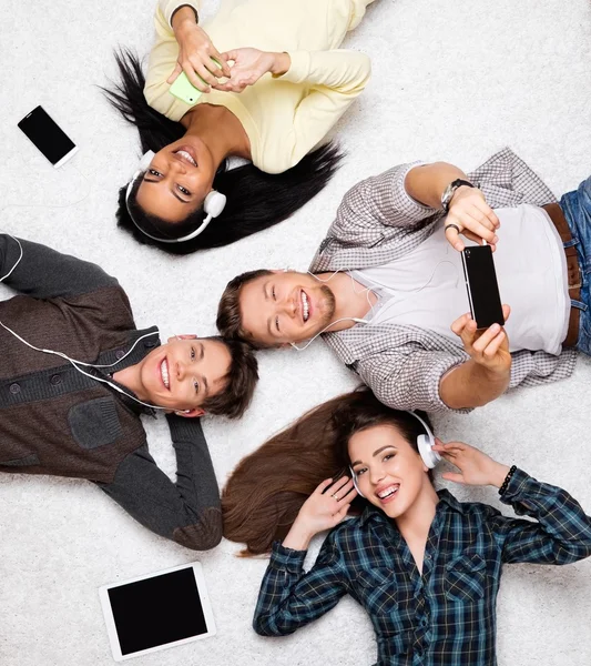 Freunde entspannen sich auf einem Teppich mit Gadgets — Stockfoto