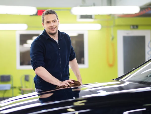 Hombre trabajador limpiando coche en un lavado de coches — Foto de Stock