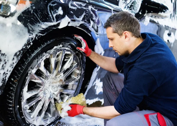 Hombre trabajador lavando ruedas de aleación de coche en un lavado de coches —  Fotos de Stock