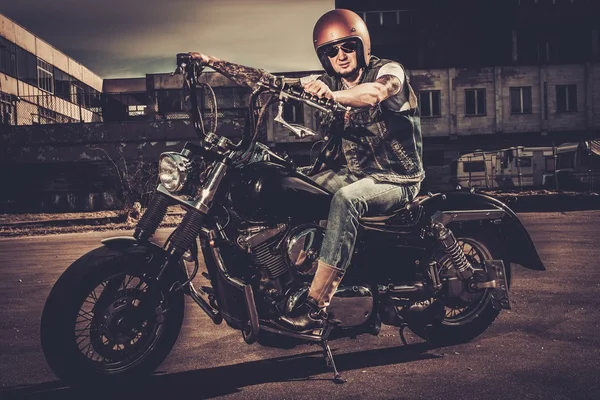 Татуированный байкер и его мотоцикл в стиле боббера на улицах города — стоковое фото