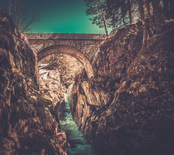 Brücke über schnellen Fluss im Bergwald — Stockfoto