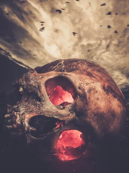 Menselijke schedel met gloeiende ogen tegen stormachtige hemel — Stockfoto
