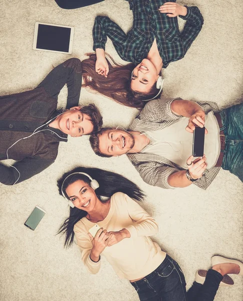 Happy multiracial vänner avkopplande på en matta med prylar — Stockfoto