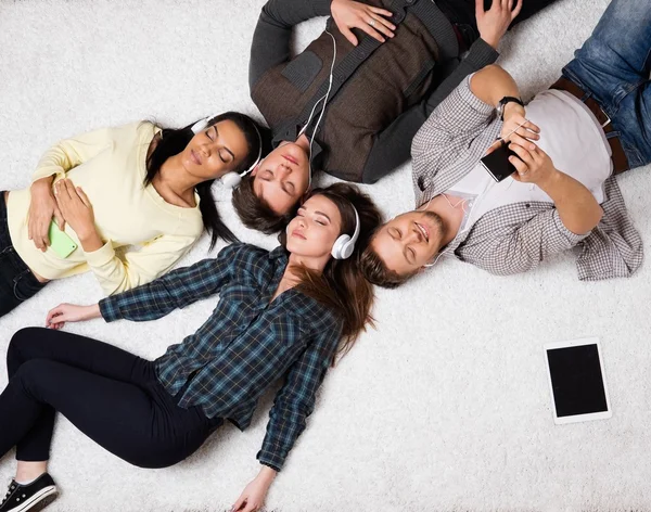 Mutlu çok ırklı arkadaşlar gadget'lar ile halı üzerinde rahatlatıcı — Stok fotoğraf