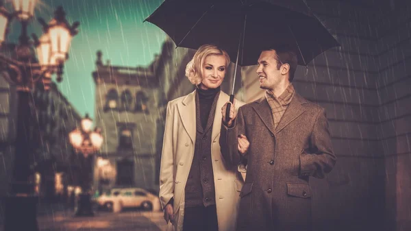 Елегантна пара з парасолькою, що йде на відкритому повітрі під дощем — стокове фото