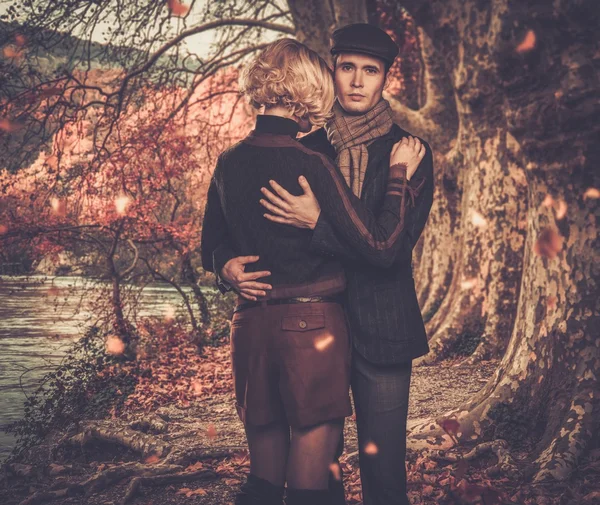 Elegant couple embracing near river in autumnal landscape — Stock Photo, Image