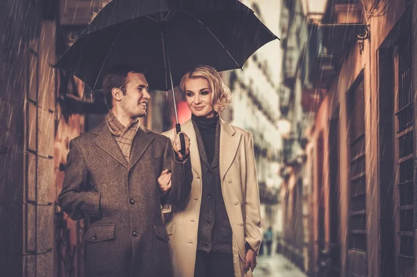 Elegante pareja con paraguas caminando al aire libre bajo la lluvia —  Fotos de Stock