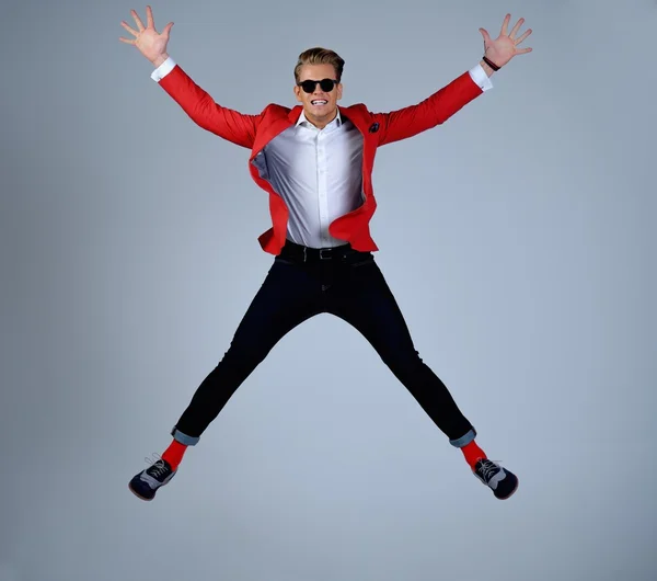 Elegante hombre con chaqueta roja que se divierte saltando — Foto de Stock