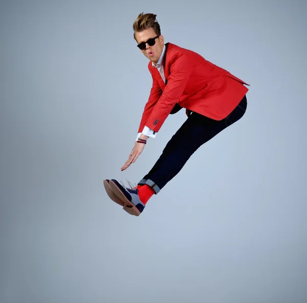 Stylish man in red jacket having fun jumping — Stock Photo, Image