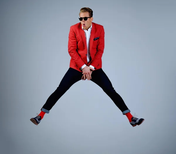 Elegante hombre con chaqueta roja que se divierte saltando — Foto de Stock