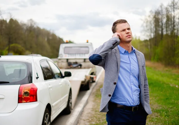 Un uomo che chiama mentre il carro attrezzi prende la sua auto rotta — Foto Stock