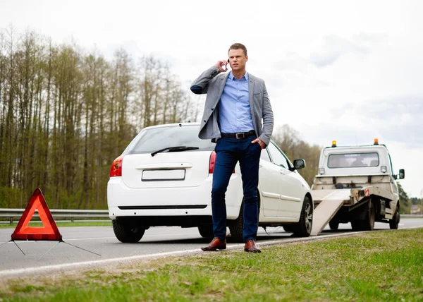 Muž volá zatímco odtahovka vyzvednout rozbité auto — Stock fotografie