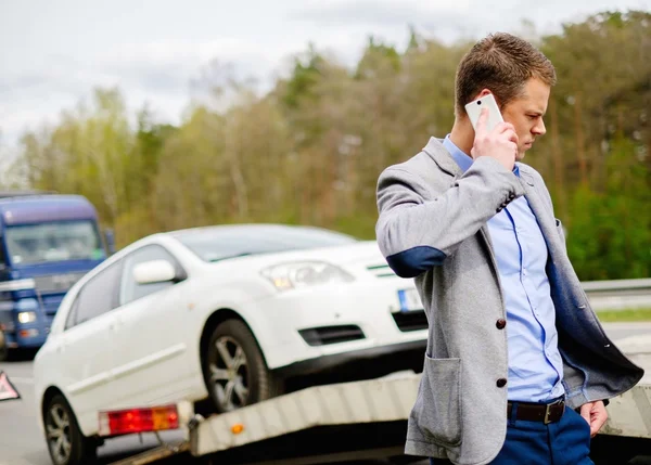 Hombre llamando mientras la grúa recoge su coche roto — Foto de Stock