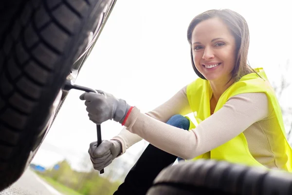Женщина меняет колесо на обочине дороги — стоковое фото
