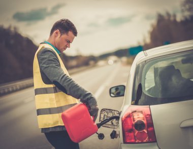 Man refuelling his car on a highway roadside  clipart