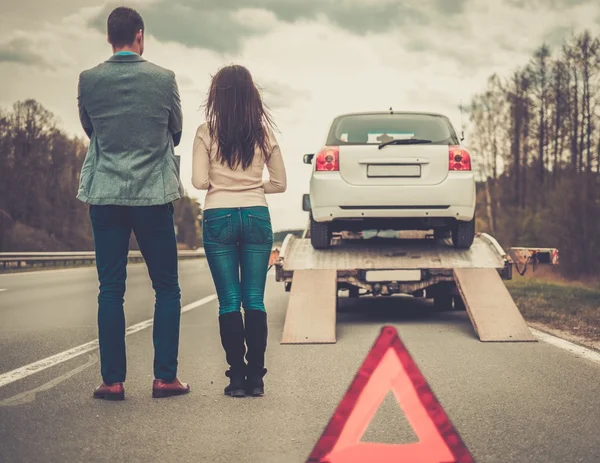 Couple près de dépanneuse ramassant voiture cassée — Photo