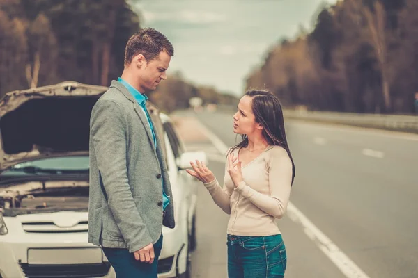 Pareja cerca de coche roto en una carretera — Foto de Stock