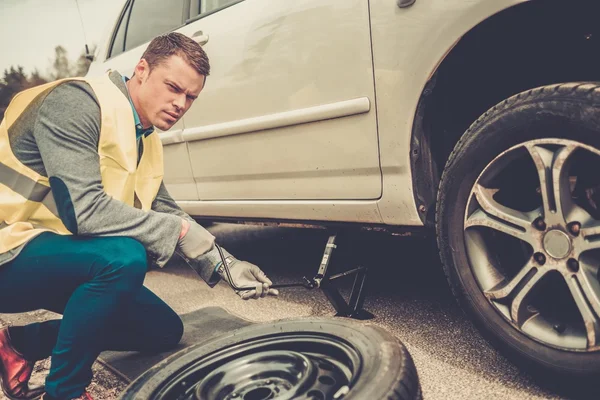 Mann wechselt Rad am Straßenrand — Stockfoto