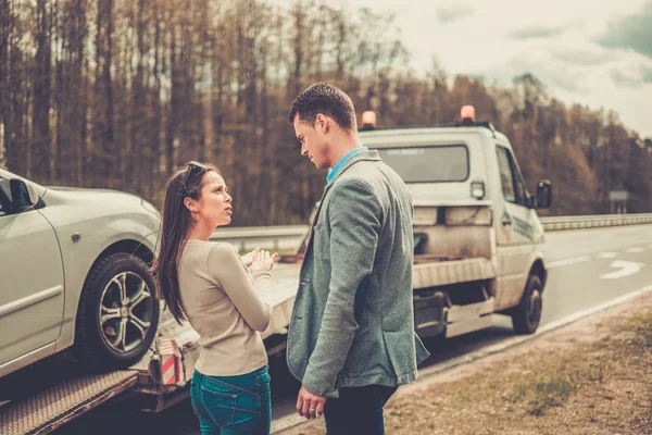 Casal perto de reboque-caminhão pegando carro quebrado — Fotografia de Stock