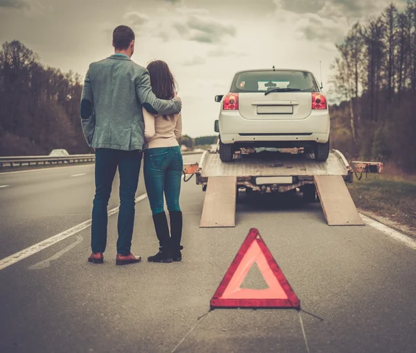 Un par cerca de la grúa recogiendo el coche roto — Foto de Stock