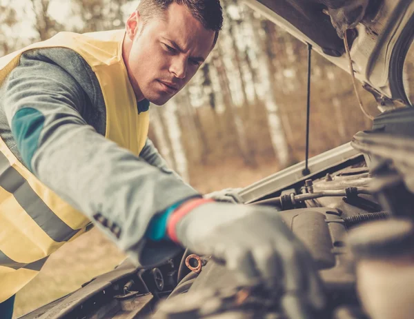 Чоловік закріплює зламаний автомобіль на узбіччі — стокове фото