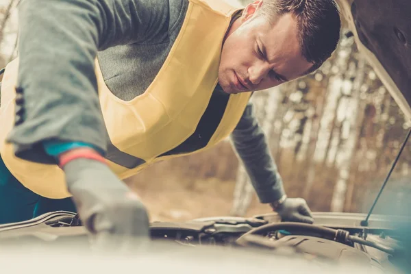 Hombre arreglando coche roto en una carretera — Foto de Stock