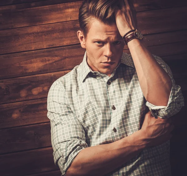 Knappe man dragen geruite shirt in houten vakantiehuis interieur — Stockfoto