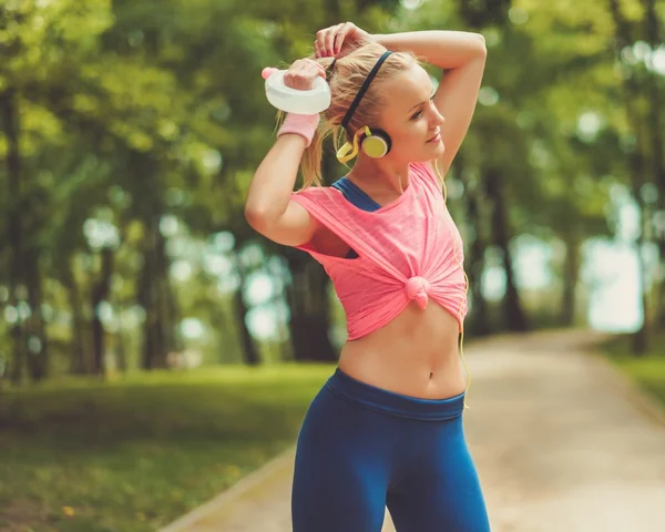 Sportiga kvinnan i en park med dricka flaska — Stockfoto