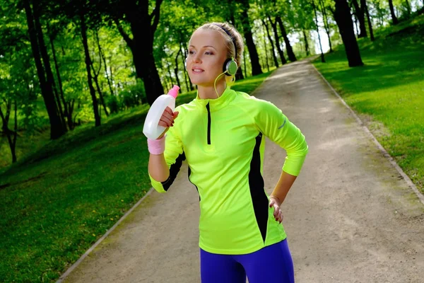 Sportiga kvinnan i en park med dricka flaska — Stockfoto