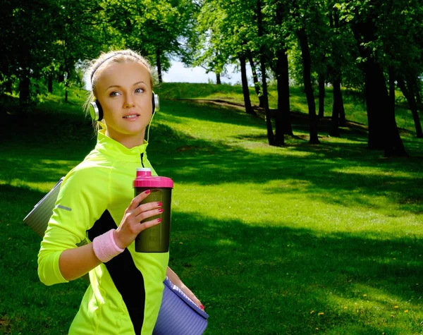 Sportieve lachende vrouw in een park met fles — Stockfoto