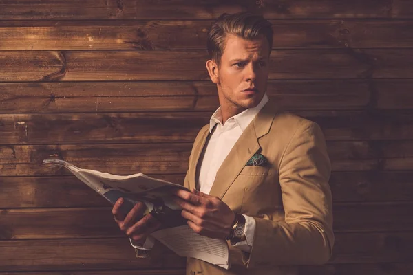 Stylish man with newspaper in rural cottage interior — Stock Photo, Image