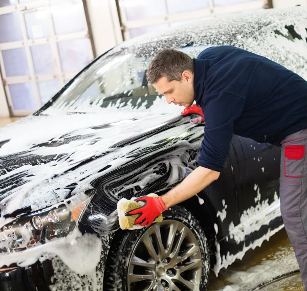 Uomo lavoratore lavaggio auto di lusso con spugna — Foto Stock