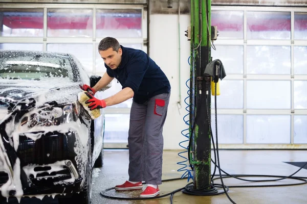 Homme travailleur laver voiture de luxe avec éponge — Photo