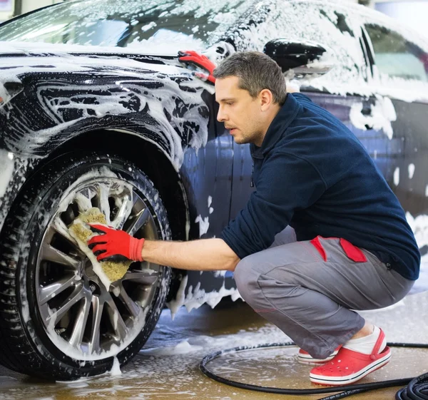 Man worker washing car's alloy wheels — Stock fotografie