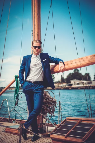 Stylish wealthy man on a luxury wooden regatta — Stock Photo, Image