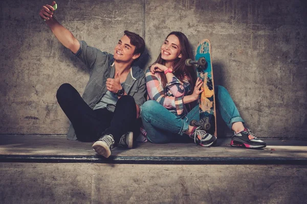 Casal jovem com skate tomando selfie — Fotografia de Stock