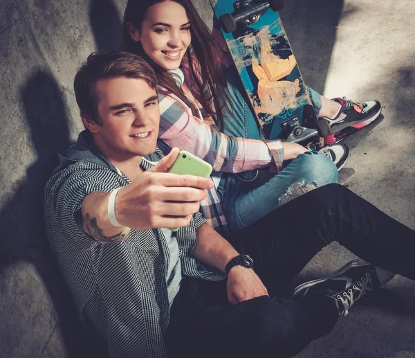 Casal jovem com skate tomando selfie — Fotografia de Stock