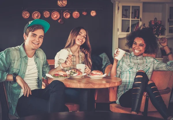 Vrolijke multiraciale vrienden eten in een café — Stockfoto