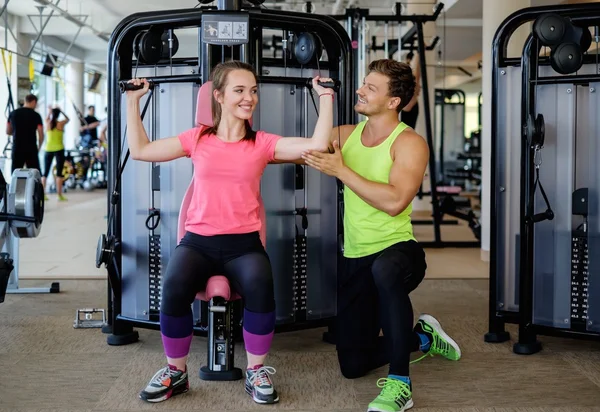 Trainer explaining how to use training machine in a gym — Stock Photo, Image