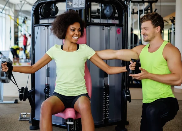 Trainer erklärt, wie man ein Trainingsgerät im Fitnessstudio einsetzt — Stockfoto