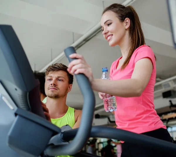 Treinador explicando como usar a máquina de treinamento elíptico — Fotografia de Stock