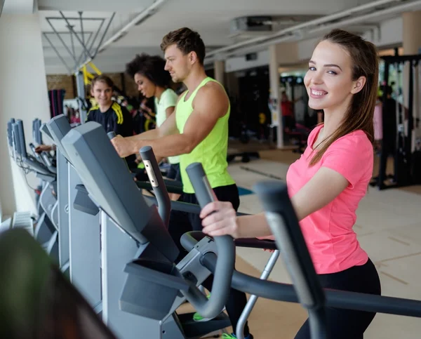 Les personnes qui font de l'exercice sur un appareil d'entraînement cardio dans une salle de gym — Photo