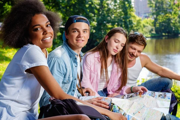 Amis multiraciaux touristes dans un parc avec la carte — Photo